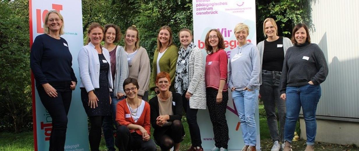 Theaterpädagogische Werkstatt Eine Personengruppe steht vor einem Gebäude.