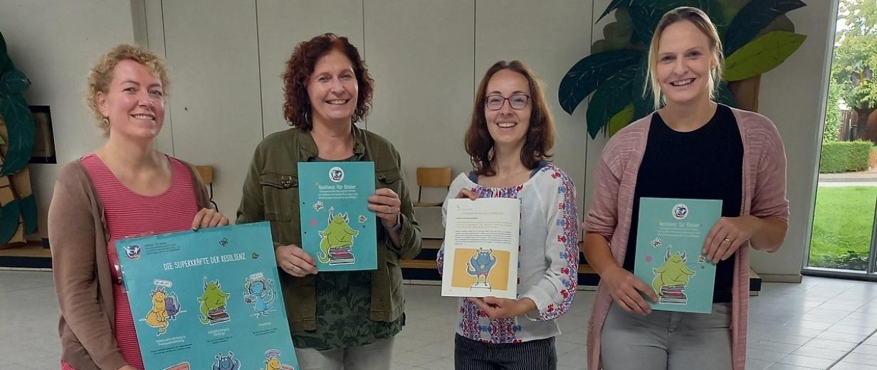 Resilienz Grundschulen TPW Vier Personen stehen im Foyer eines Gebäudes.