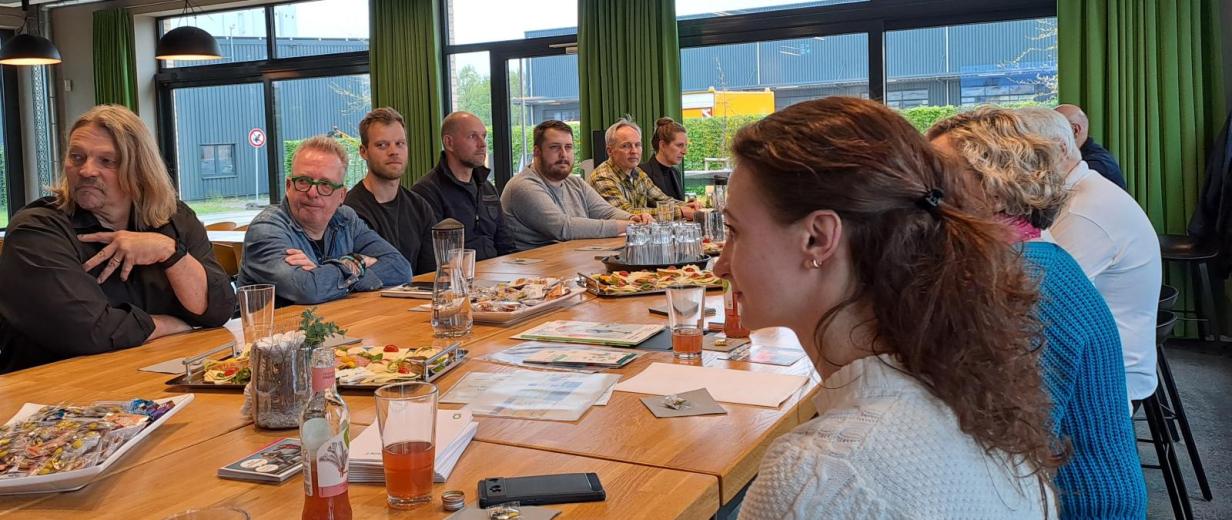 Eine Personengruppe sitzt um einen großen Tisch herum.