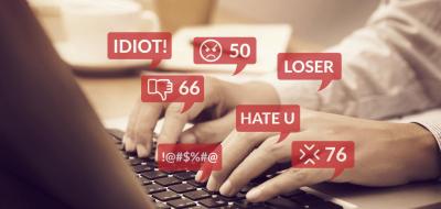 Hände auf einer Computertastatur. Rote Sprechblasen.