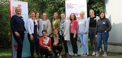Eine Personengruppe steht vor einem Gebäude.