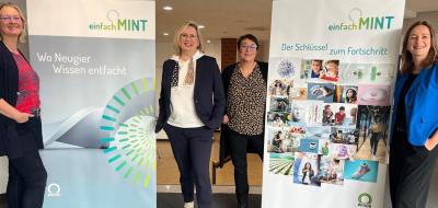 Vier Personen stehen zwischen Roll-Up-Postern.