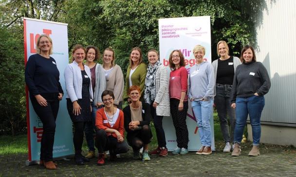 Eine Personengruppe steht vor einem Gebäude.