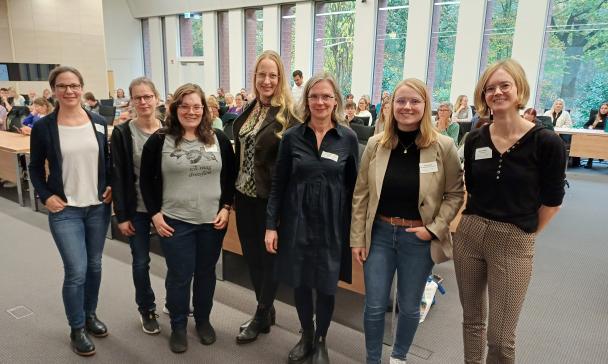 Eine Personengruppe steht in einem Veranstaltungssaal.